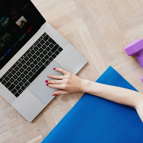 crop-woman-with-laptop-and-dumbbell-on-sports-mat-4498362